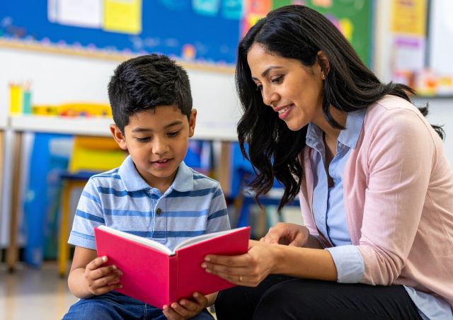Child practicing sight words with their teacher sharing a book in class